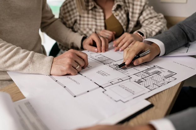 Real estate agent reviewing a home blueprint with buyers