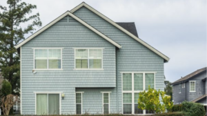 A modern home with blue siding on a cloudy day.